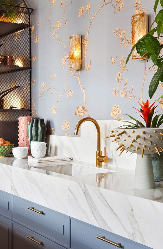 a refined kitchen with gold floral wallpaper, gold sconces, gold fixtures and a bowl with gold spikes is cool