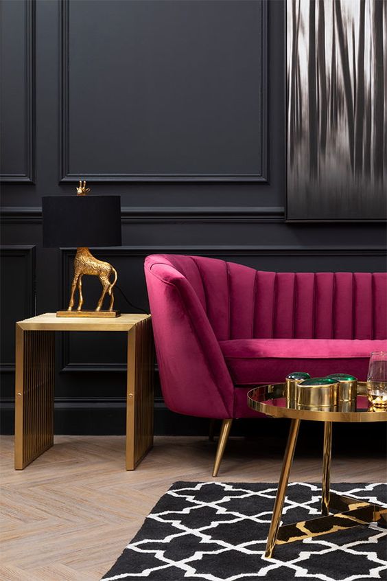 a refined living room with black paneled walls, a fuchsia loveseat, a gold table and a gold side table, gold and black table lamp