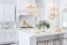 a refined white kitchen with a gold pendant lamp and matching stools is a beautiful and lovely space to enjoy