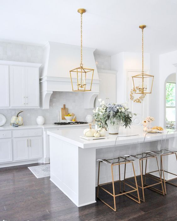 a refined white kitchen with a gold pendant lamp and matching stools is a beautiful and lovely space to enjoy