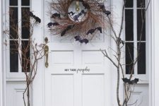 a twig Halloween wreath with black bats is a lovely and traditional idea to decorate your front door for Halloween