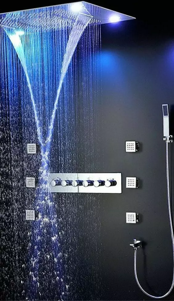 a welcoming shower space wiht black walls, a large rain shower head with colored lights and stainless steel fixtures