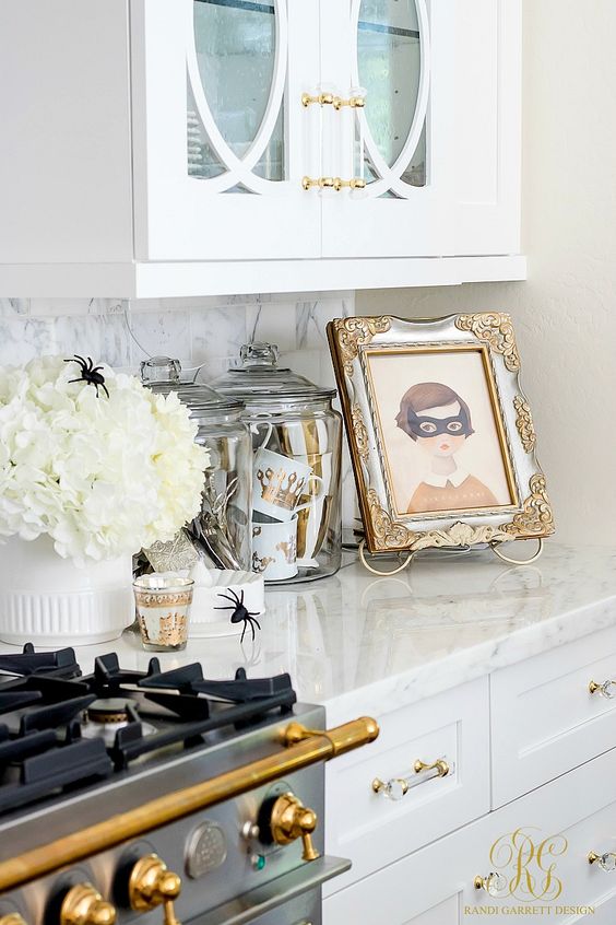 a white floral arrangement with spiders, jars with glam striped and crown mugs and a cool artwork in a refined frame