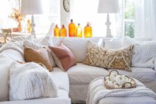 amber colored bottles and a basket with white pumpkins make this white living room more fall-like
