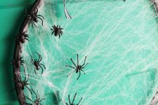 an embroidery hoop Halloween wreath with spider net and small black spiders plus a striped bow is easy to DIY