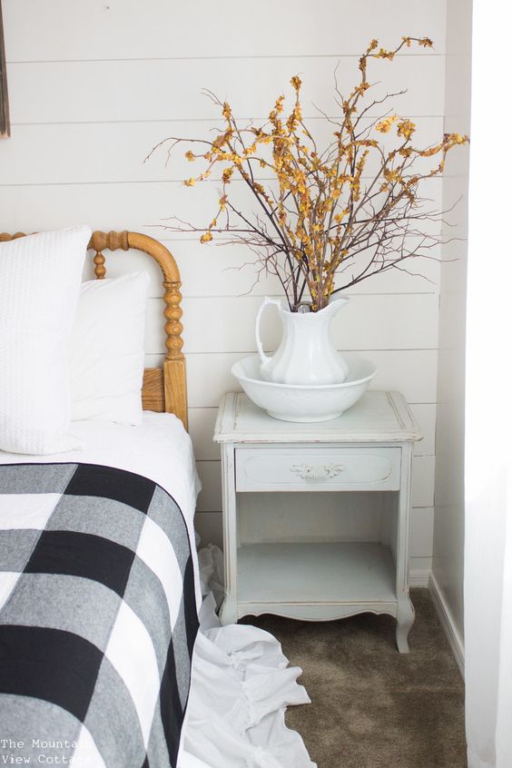branches with orange blooms in a jug is a cool idea for a rustic fall bedroom and are cool for a Nordic feel