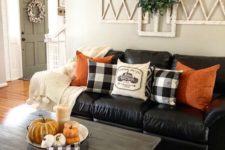 bright orange pillows and a bowl with pumpkins and candles are added for a fall touch