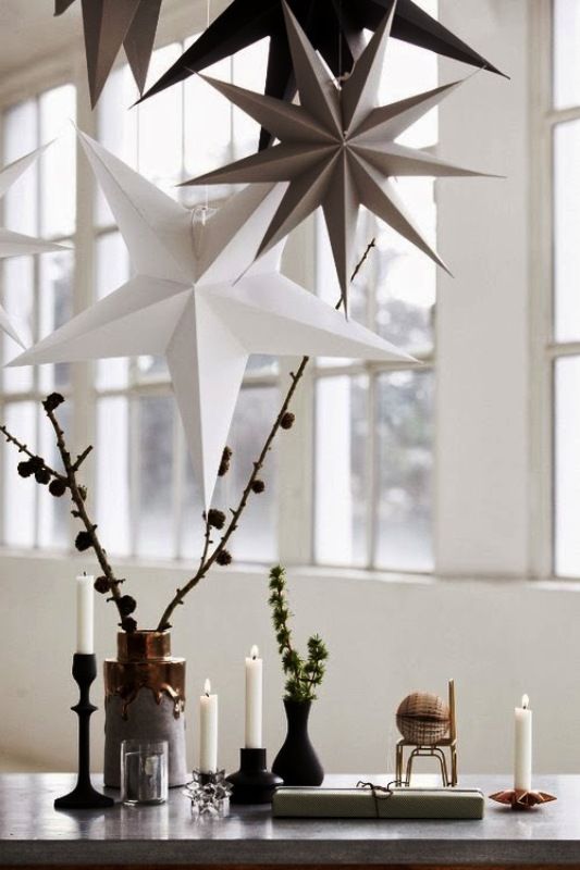fall Nordic decor with branches with pinecones, greenery in matte black vases, candles and a glass