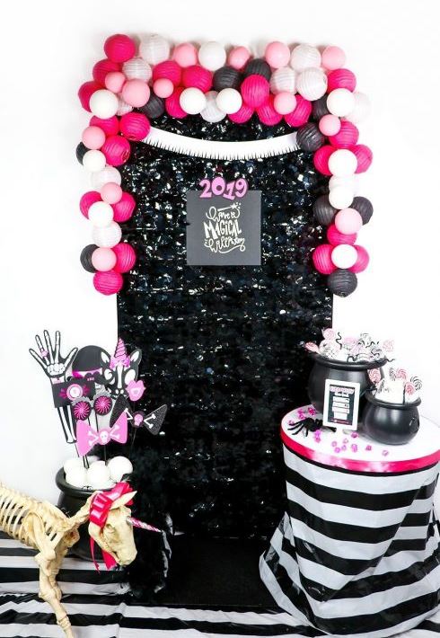 glam Halloween decor wiht a black sequin cover, pink, blush and black balloons, hot pink and purple props and a skeleton