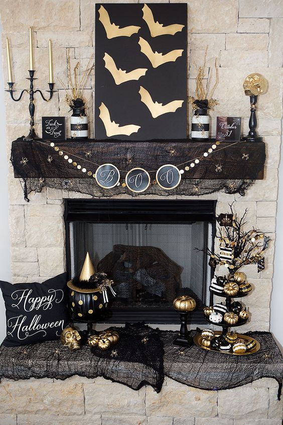 Glam black and gold Halloween decor   an artwork with gold bats, a gold garland, gold candles, pumpkins and black mesh