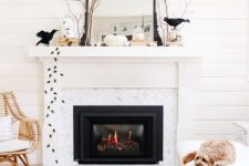 a Halloween mantel with blackbirds, spiders, branches, white pumpkins, a mirror in a black frame is all cool