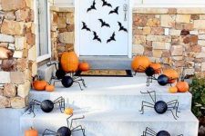 a Halloween porch with black bats on the door, orange pumpkins and fun black spiders is a fun and playful solution for the fall