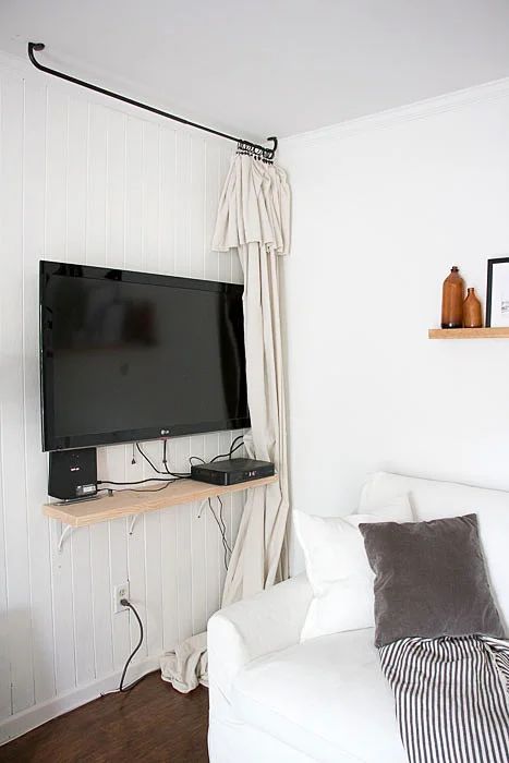 a TV and a shelf on the wall hidden with a white curtain are a simple and practical idea, and you can realize it very fast