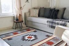 a boho living room accented with a grey, red and tan printed rug that makes it cool and bold and gives personality to it