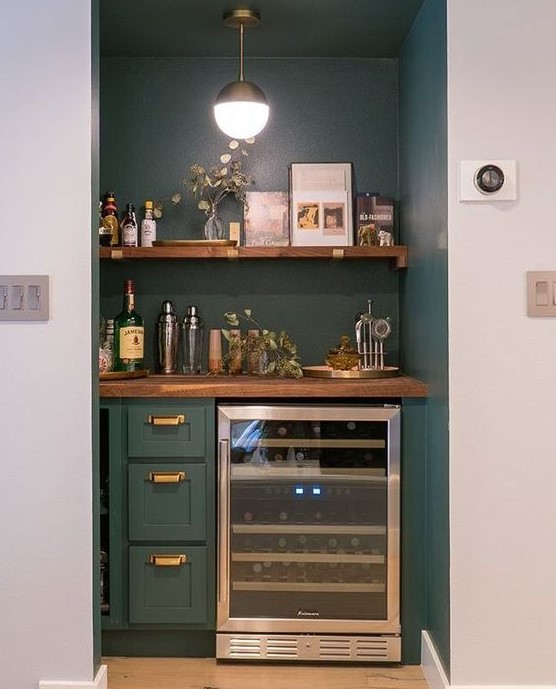 A built in home bar with an open shelf, drawers and a fridge plus some greenery is a chic idea