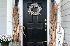 a chic and fresh rustic front door with corn husks, heirloom pumpkins and white blooms in pots for Thanksgiving