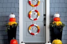 a colorful Halloween porch with colorful mini wreaths, colorful pumpkins on the steps and in the planters