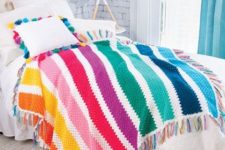 a colorful striped crochet blanket with tassels and matching pillow cases with tassels for adding fun to the bedroom