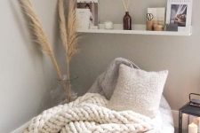 a cozy Nordic reading nook with open shelves, a beanbag chair, a chunky crochet blanket and a neutral pillow, some magazines and books