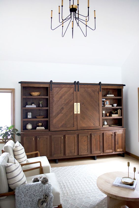 a farmhouse living room with a large rich-stained storage unit and a TV inside it, this unit takes over the whole room and creates a contrast