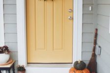 a foliage wreath, fall pumpkins and some blooms in pots make the porch cozy and Thanksgiving-ready
