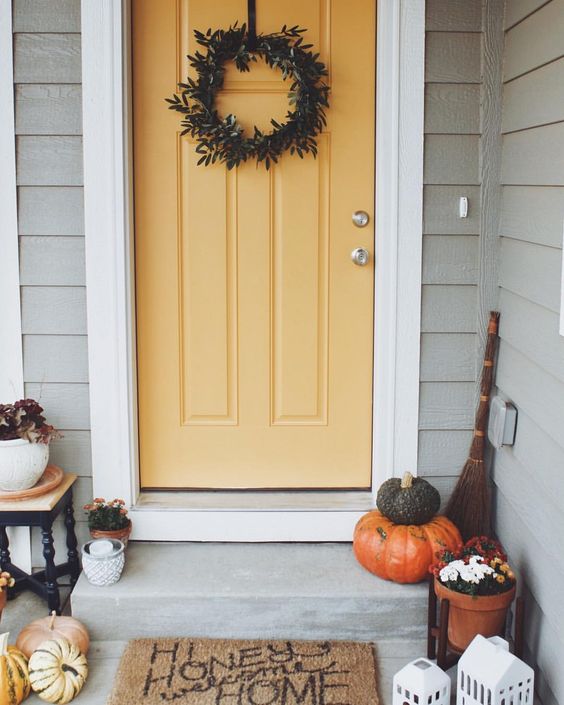 A foliage wreath, fall pumpkins and some blooms in pots make the porch cozy and Thanksgiving ready