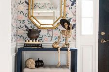 a glam Halloween console table with silver, gold and black pumpkins, a gold skeleton in a witch hat and a skull