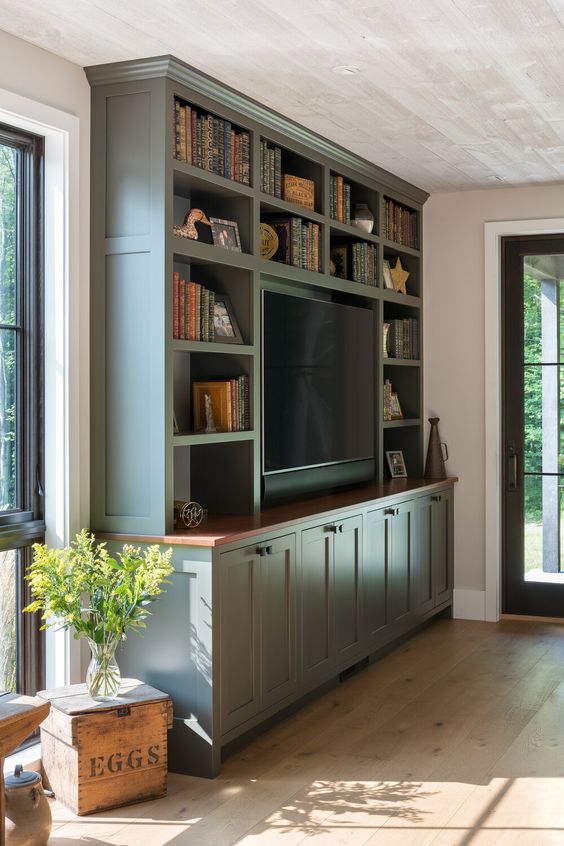 a green storage unit with books and a TV in the center is a cool solution for a modern farmhouse space, it looks cool