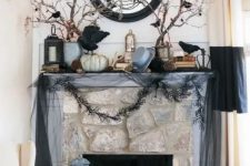 a haunted Halloween mantel with blackbirds, branches, garlands, a mirror and some pumpkins