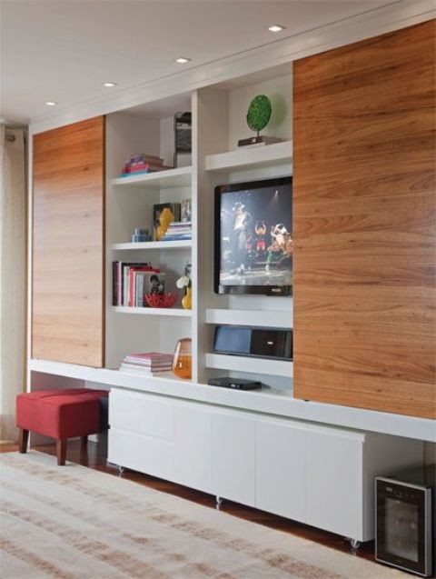 a large white storage unit with sleek sliding doors hiding the whole unit or the TV when needed