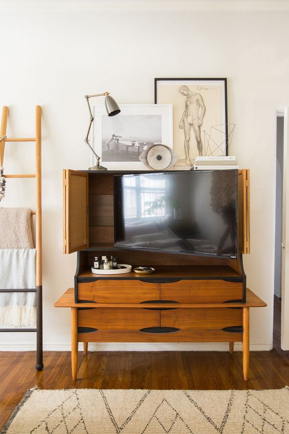 A light stained mid century modern storage unit with a TV inside is a cool way to hide a TV without spoiling the interior