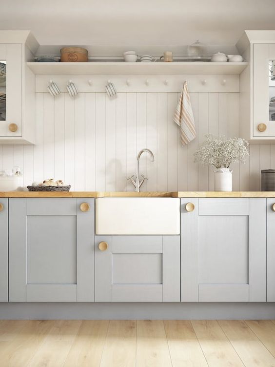 a lovely cottage kitchen with beadboard walls, grey cabinets, butcherblock countertops, some blooms and striped touches