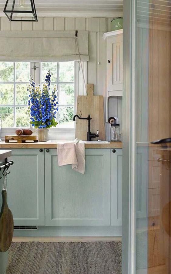 a lovely cottage kitchen with beadboard walls, light blue shaker cabinets, butcherblock countertops, pendant lamps