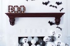 a modern Halloween mantel with marquee letters, bats and lots of black and white balloons in the fireplace