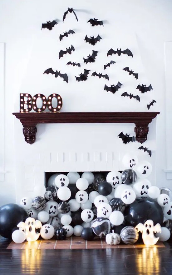 a modern Halloween mantel with marquee letters, bats and lots of black and white balloons in the fireplace