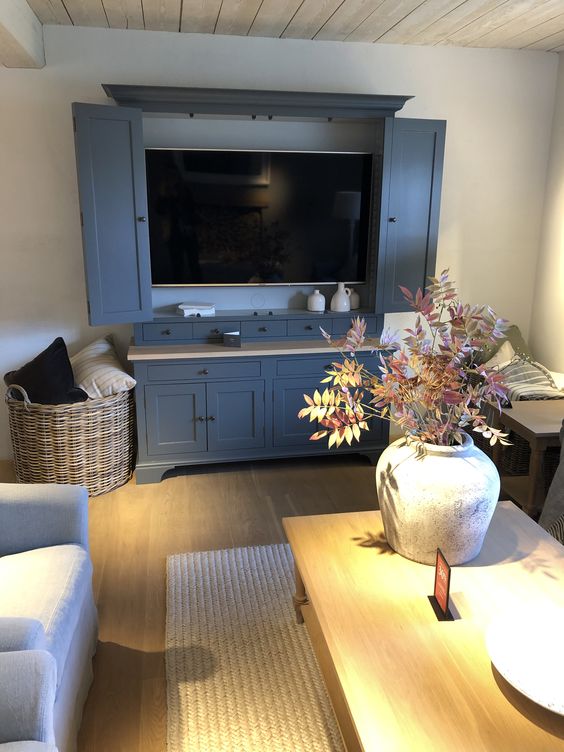a modern farmhouse living room with a grey TV unit and a TV hidden with matching doors, white seating furniture and a coffee table
