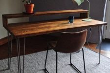 a modern industrial working space with a wooden desk on hairpin legs and a leather metal chair plus a table lamp