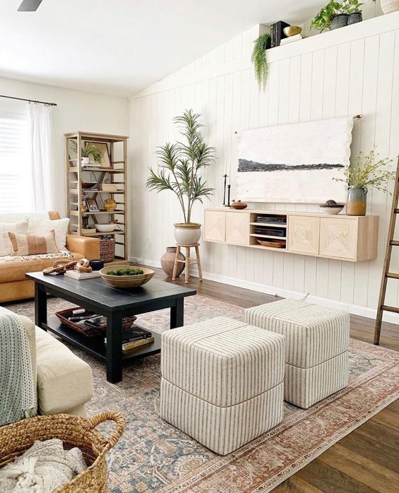 a modern rustic living room with a TV unit on the wall and a TV hidden with a fabric artwork is a cool idea