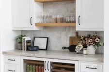a neutral modern farmhouse home bar with cabinetry and open shelves, wine coolers, potted greenery, glasses and wine bottles