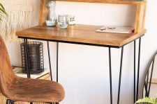 a pretty and small working space with a wooden desk with hairpin legs and an additional shelf attached, a leather and metal chair