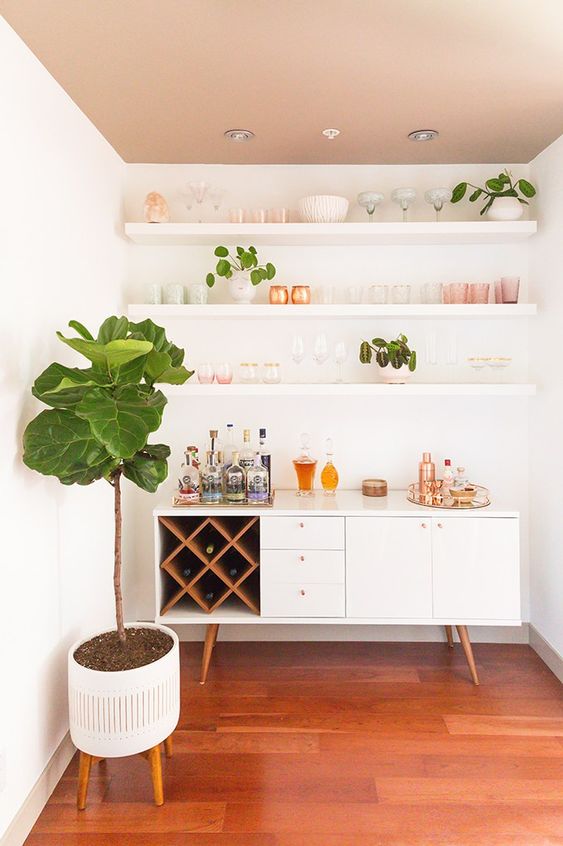 A pretty mid century modern home bar with open shelves, a chic credenza with a storage compartment with wine bottles, potted greenery