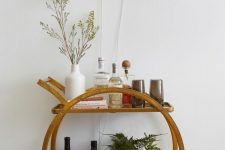 a pretty modern home bar of a brass bar cart and a neon light over it, with wine bottles, greenery and glasses is a lovely idea
