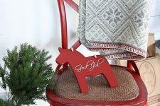 a red chair with a grey embroidered blanket, a red horse decoration, red buckets and some red hearts on the wall for Christmas