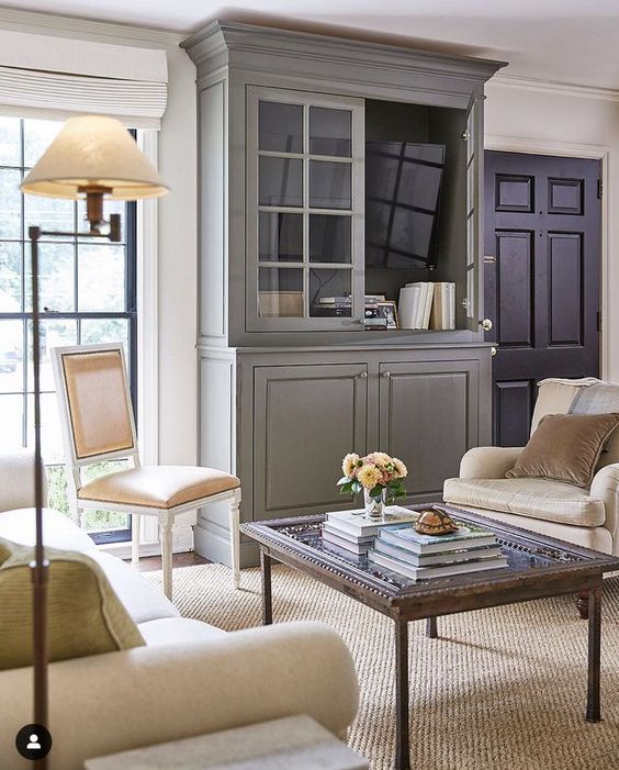 a refined and chic living room with a grey storage unit and a TV inside it that can be hidden with its doors