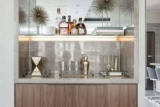 a refined built-in home bar with neutral marble, lit up shelves and sleek drawers is very chic and stylish