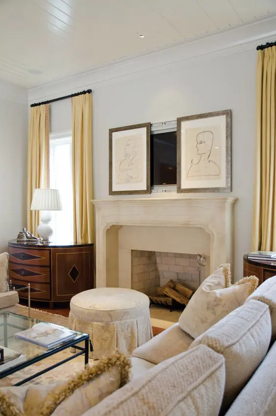 a refined living room with a large stone clad fireplace, a TV hidden with artwork and chic vintage furniture around