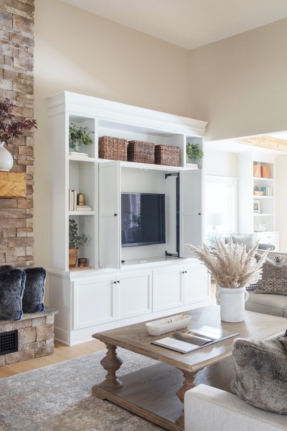 a rustic living room with a white storage unit that includes a TV that can be hidden with usual doors is a super cool idea