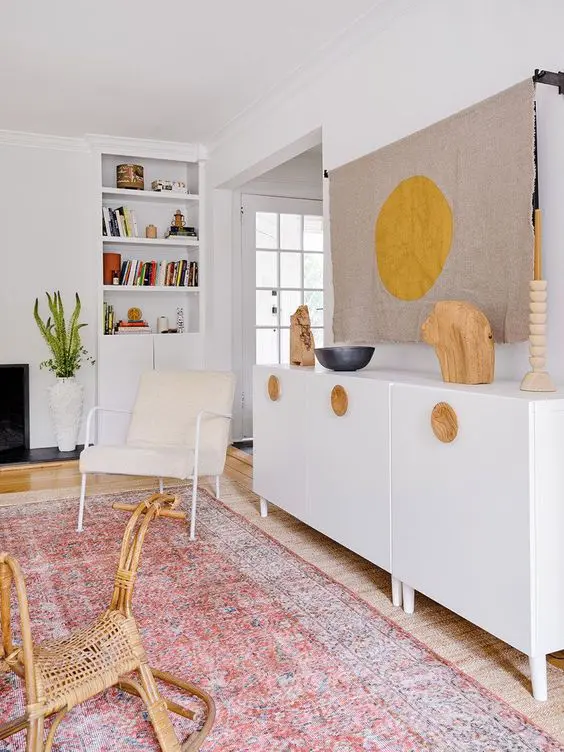 A serene boho space with a fireplace, built in shelves, a credenza, a TV hidden with a piece of fabric is a cool space