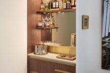 a sleek modern home bar of stained cabinets, open shelves, a mirror and touches of gold for a chic and lovely look