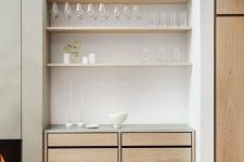 a small built-in home bar with open shelves, sleek drawers and candles is a chic addition to your living room